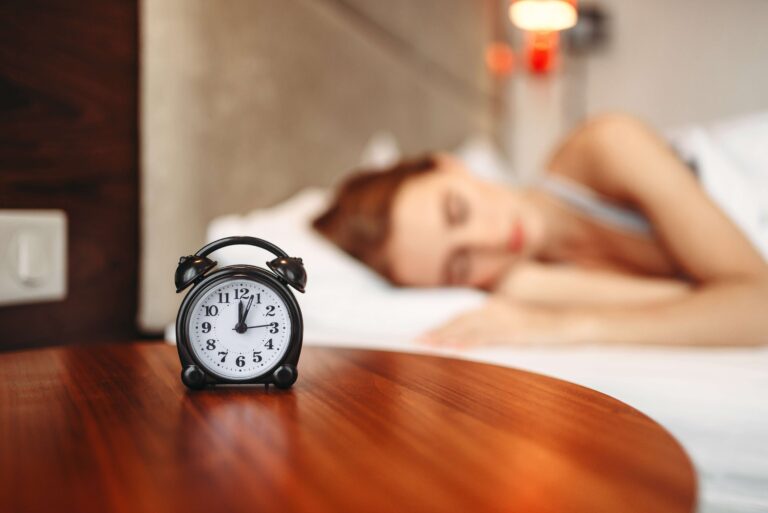 A woman next to an alarm clock that improved her sleep and mental health.